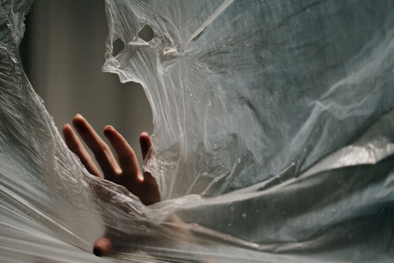 A hand breaking through a web