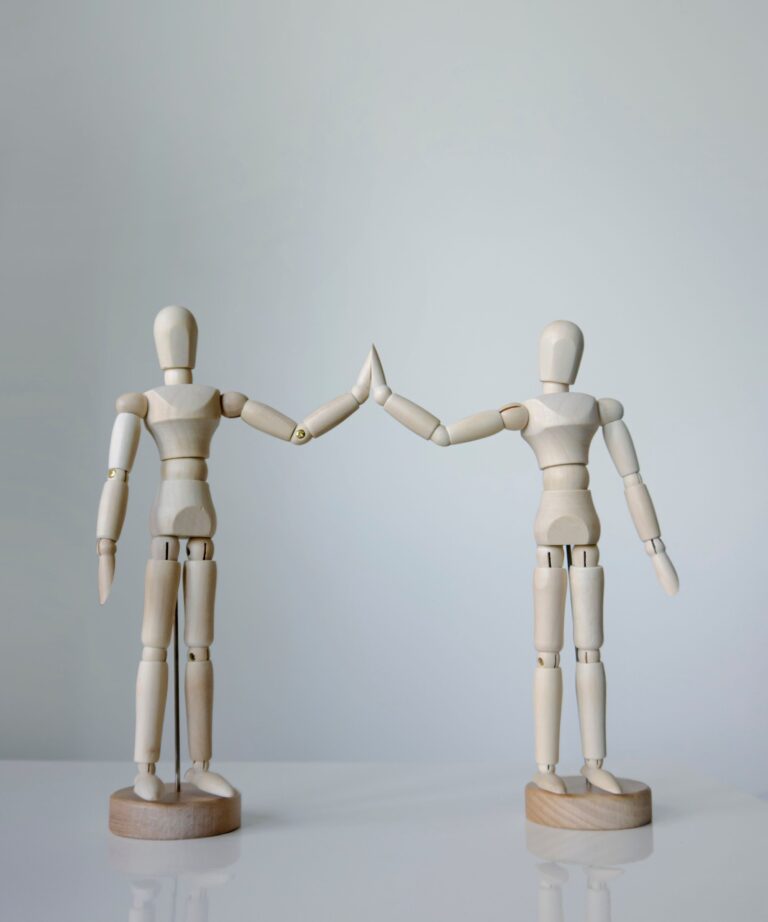 Two wooden figurines touching hands high