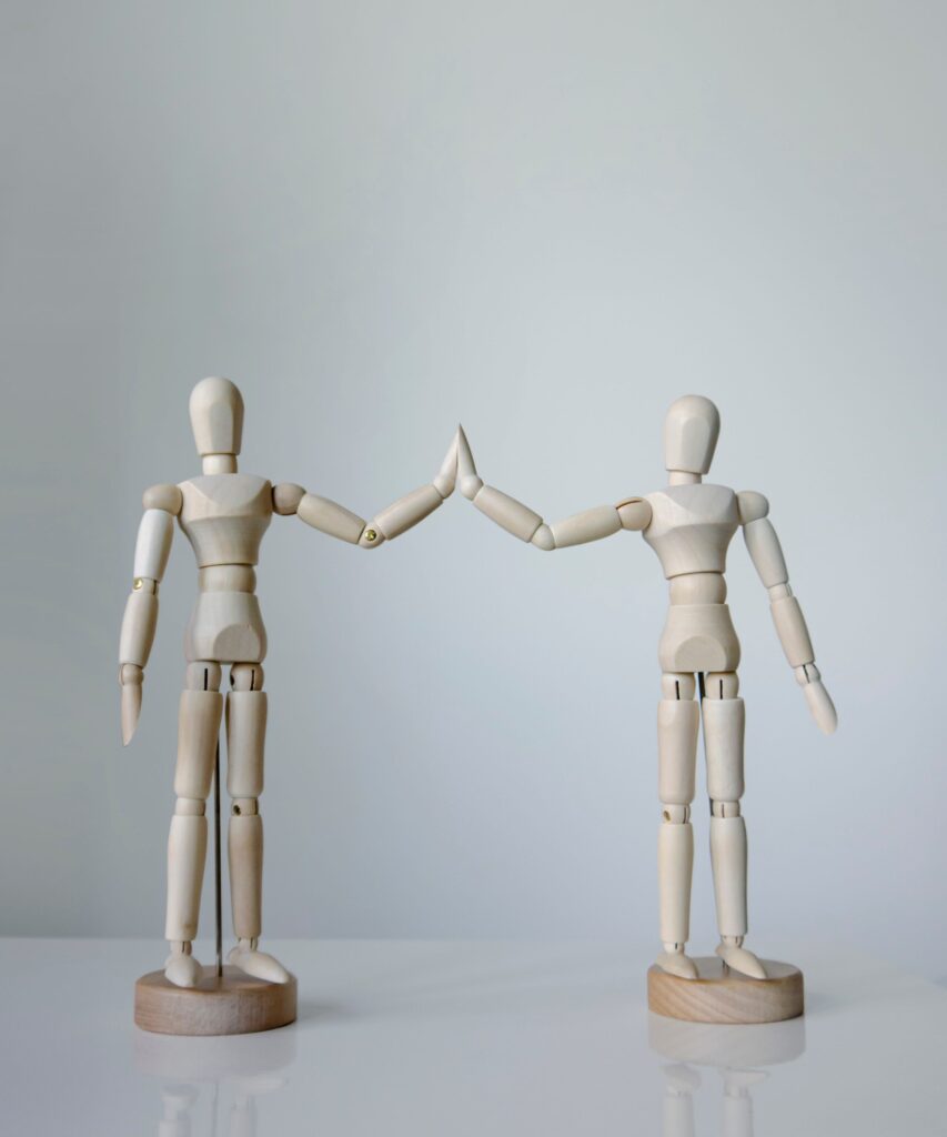 Two wooden figurines touching hands high